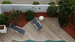 A wooden deck with a swimming pool, two lounge chairs, and a small table. - Sandbar Bed & Breakfast (Nags Head)