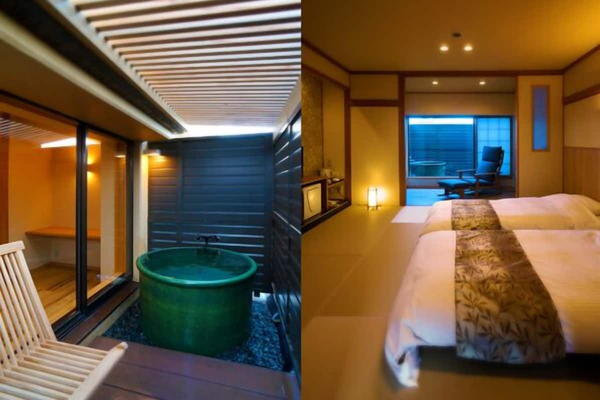 A modern hotel room with a large bed, a sitting area with a chair, a large window, and a green tub.