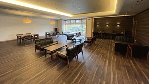A spacious conference room with a long table, several chairs, a sofa, and a small stage area. - Hotel Hisagoso (Shibata)