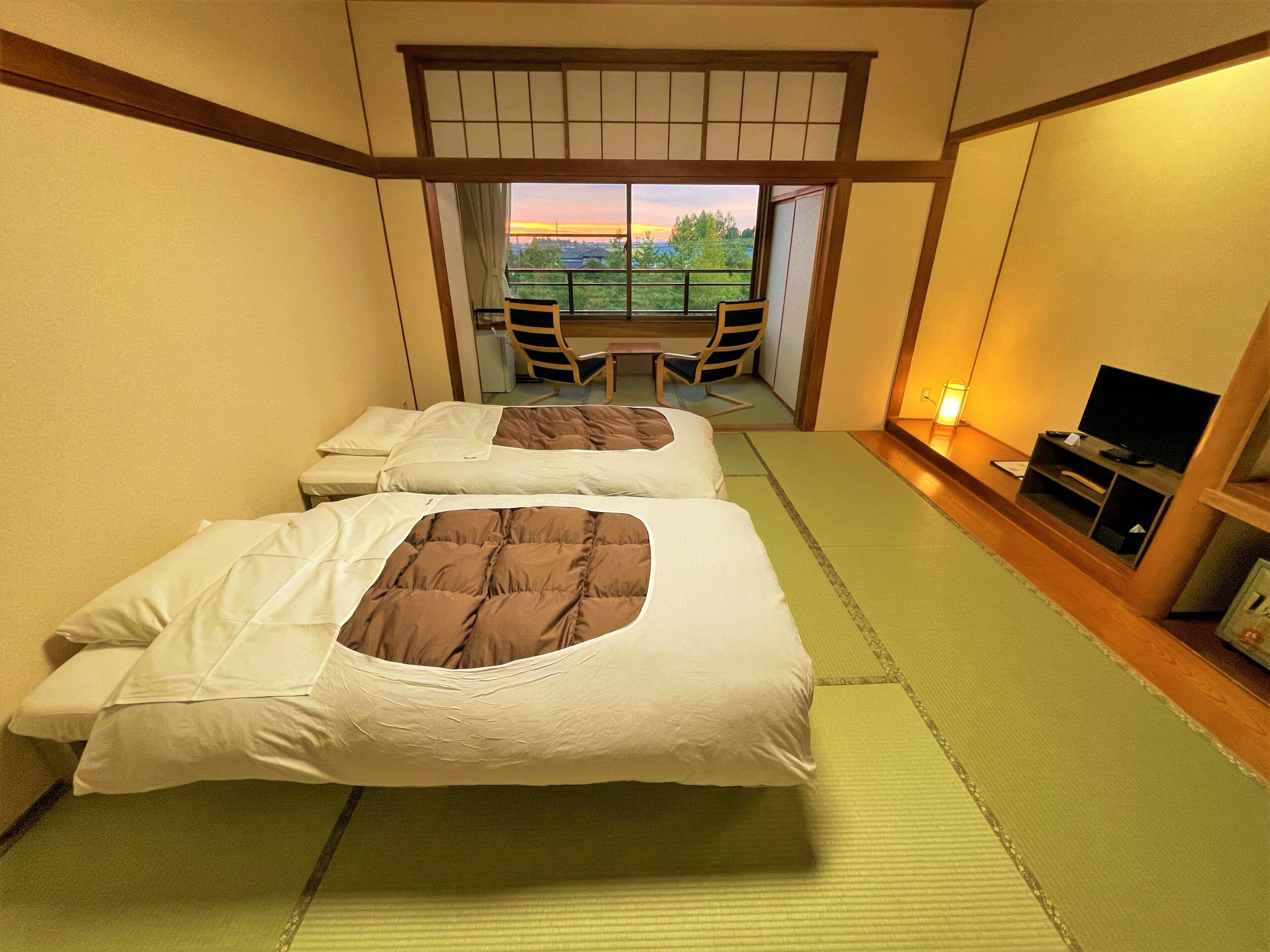 A hotel room with two beds, a TV, and a view of the outdoors.