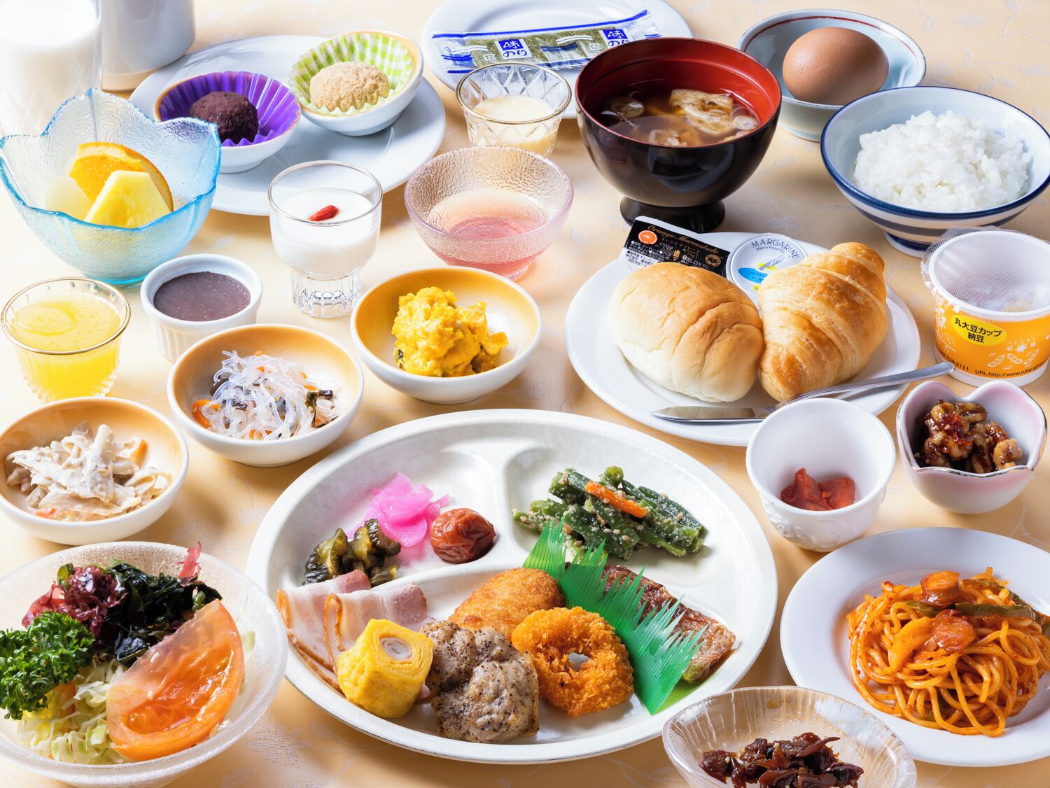 A variety of dishes including sushi, sashimi, and pasta, arranged on a table.