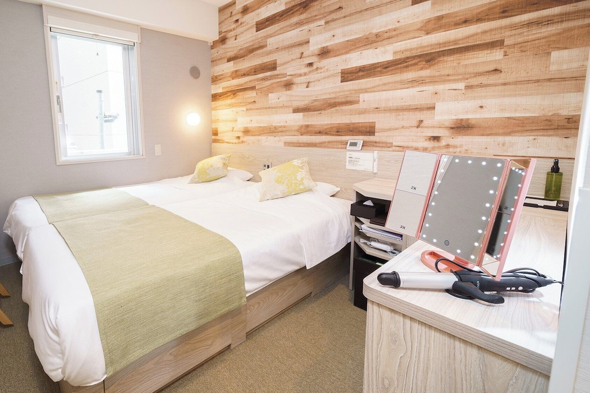 A bedroom with a bed, bedside table, mirror, and wooden wall paneling.