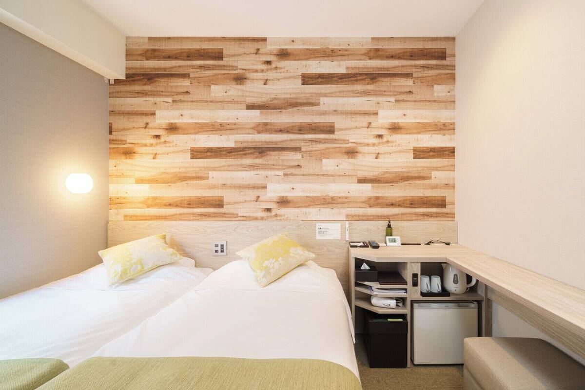 Una camera da letto con pannello in legno, un letto con cuscini, un comodino con una sveglia e un angolo cottura.