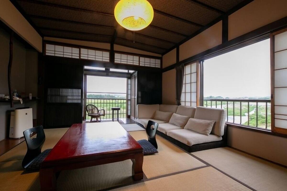 Una tradizionale stanza giapponese con pavimento in tatami, un tavolino basso, un divano e porte scorrevoli.