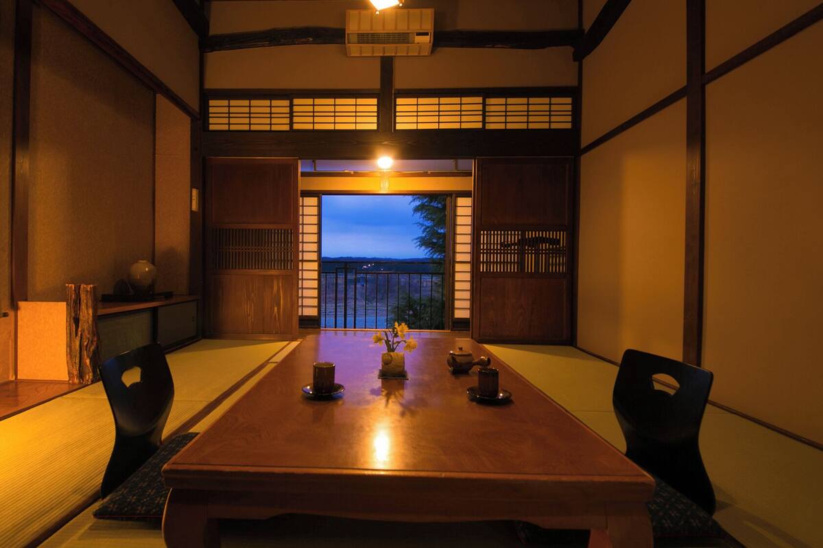 Una tradizionale stanza giapponese con pavimento in tatami, un tavolino e porte scorrevoli.
