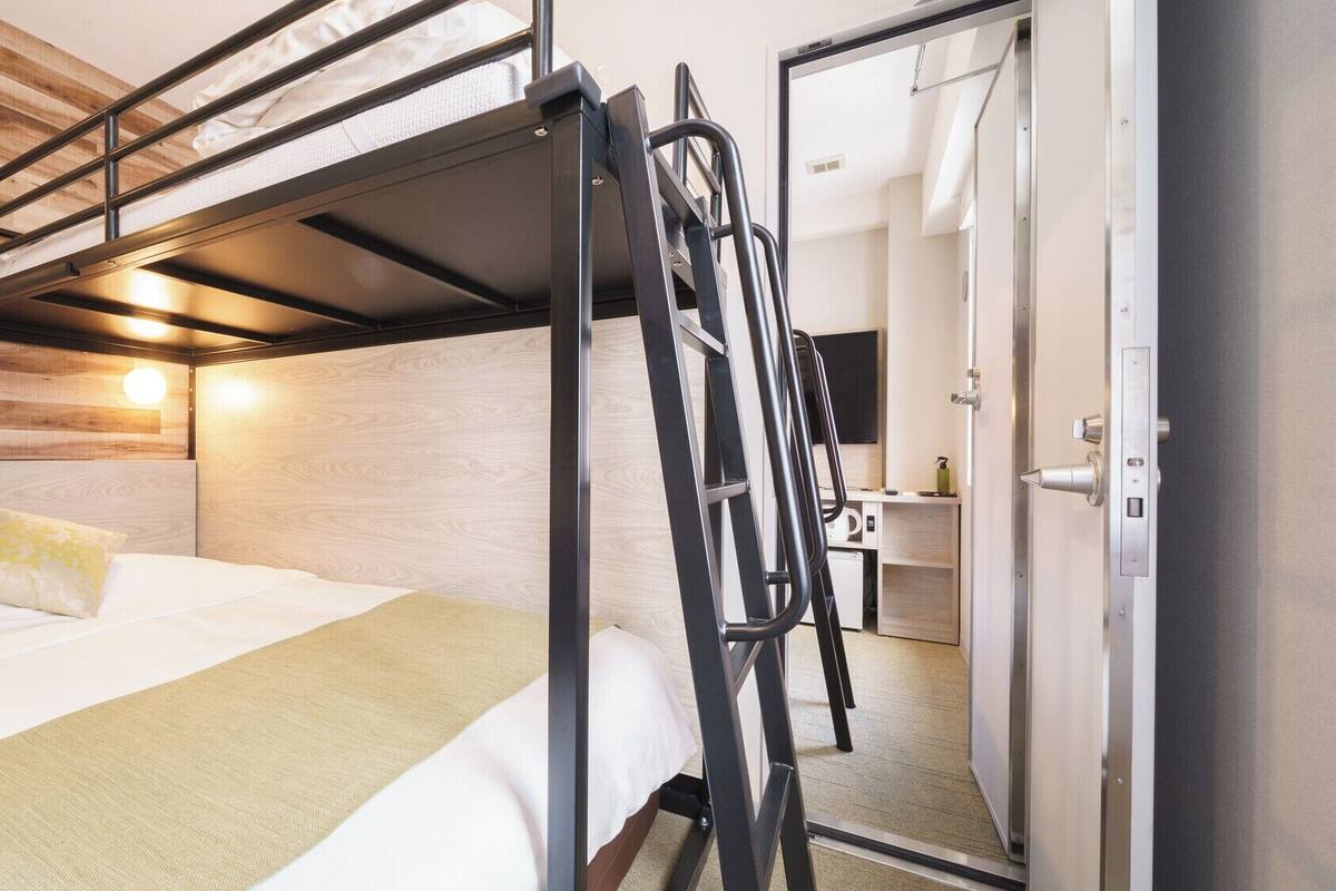 Un letto a castello con una scala, un comodino, uno specchio e un muro in legno.