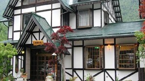 A traditional half-timbered building with a steeply pitched roof, large windows, and a sign indicating a restaurant. - Shinhotaka Onsen Resort In Chirorian (Takayama)