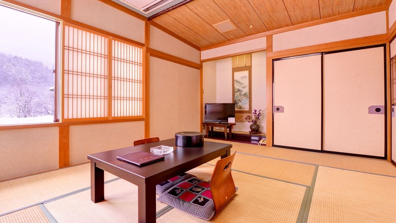 A traditional Japanese room with tatami flooring, a low table, a television, and sliding doors.
