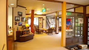 A hotel lobby with a reception desk, chairs, a staircase, and a glass display case. - Shinhotaka Onsen Resort In Chirorian (Takayama)