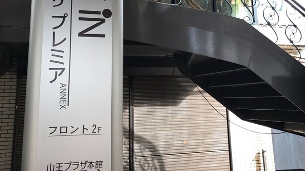 Une enseigne d’hôtel avec les inscriptions « HÔTEL » et « CHAMBRES », un escalier et une rambarde en métal.