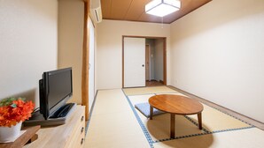 A traditional Japanese room with tatami flooring, a wooden table, a television on a stand, and a potted plant. - Tabist Chunichi Business Hotel Iseshima (Shima)