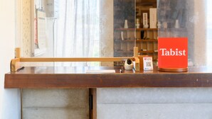 A wooden reception desk with a glass partition, a PayPay QR code, and a red 'Tabist' sign. - Tabist Chunichi Business Hotel Iseshima (Shima)