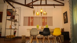 A dining area with a wooden table, four chairs, and hanging pendant lights. - YAKU eco house (La Banda de Shilcayo)