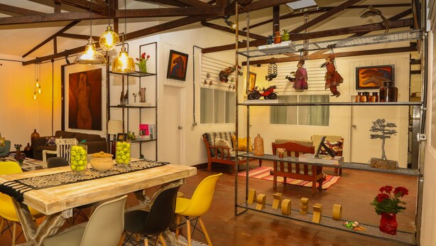 A dining area with a wooden table, yellow chairs, and hanging pendant lights. - YAKU eco house (La Banda de Shilcayo)