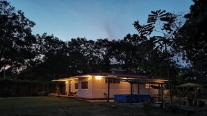 A small, single-story building with a porch and a covered outdoor seating area. - YAKU eco house (La Banda de Shilcayo)