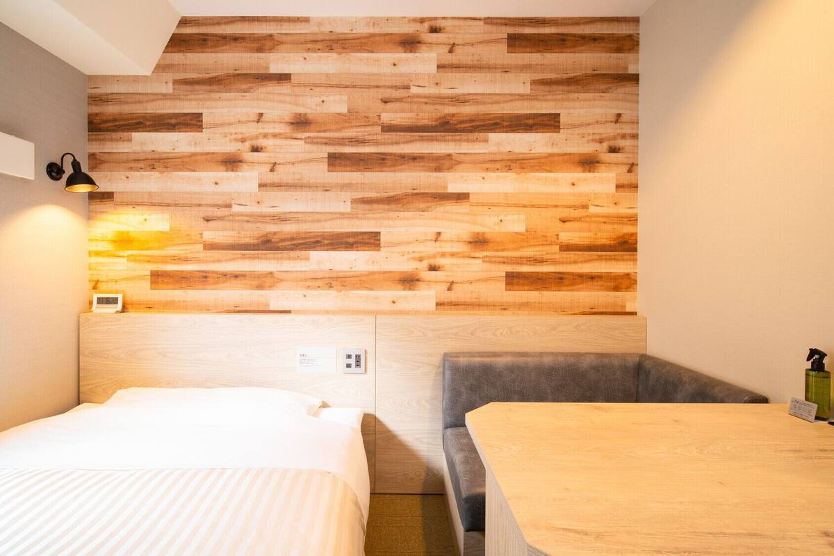 Een kleine, moderne kamer met een houten paneel, een bed, een stoel en een tafel.