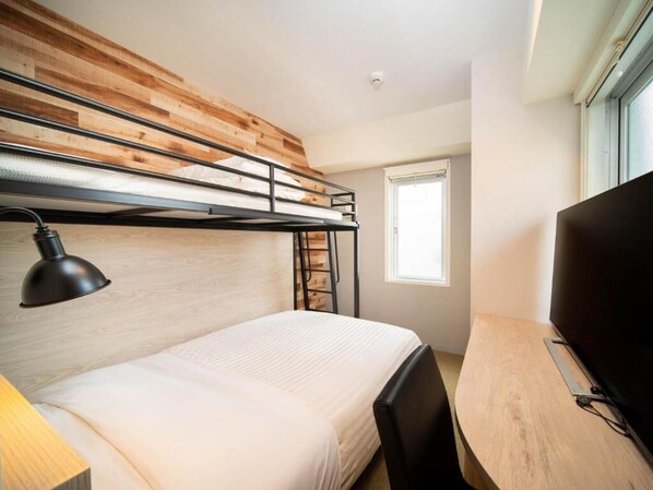 A bunk bed with a desk and a TV in a room with wooden paneling and a window.