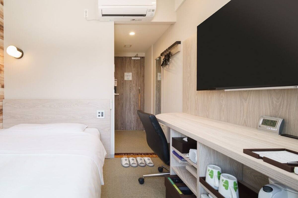 Een hotelkamer met een bed, een bureau met een flatscreen televisie, een stoel en een kleine badkamer.
