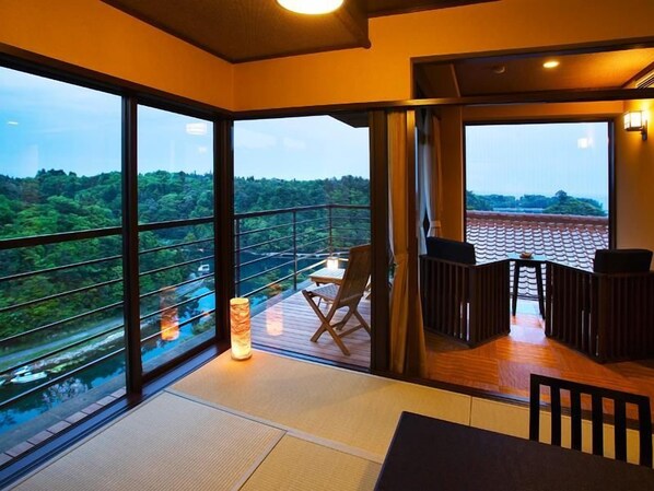A room with large windows, a wooden deck, and a table with chairs.