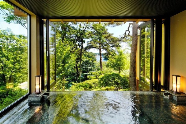 A spa area with a view of a forest, a hot tub, and two wall-mounted lamps.