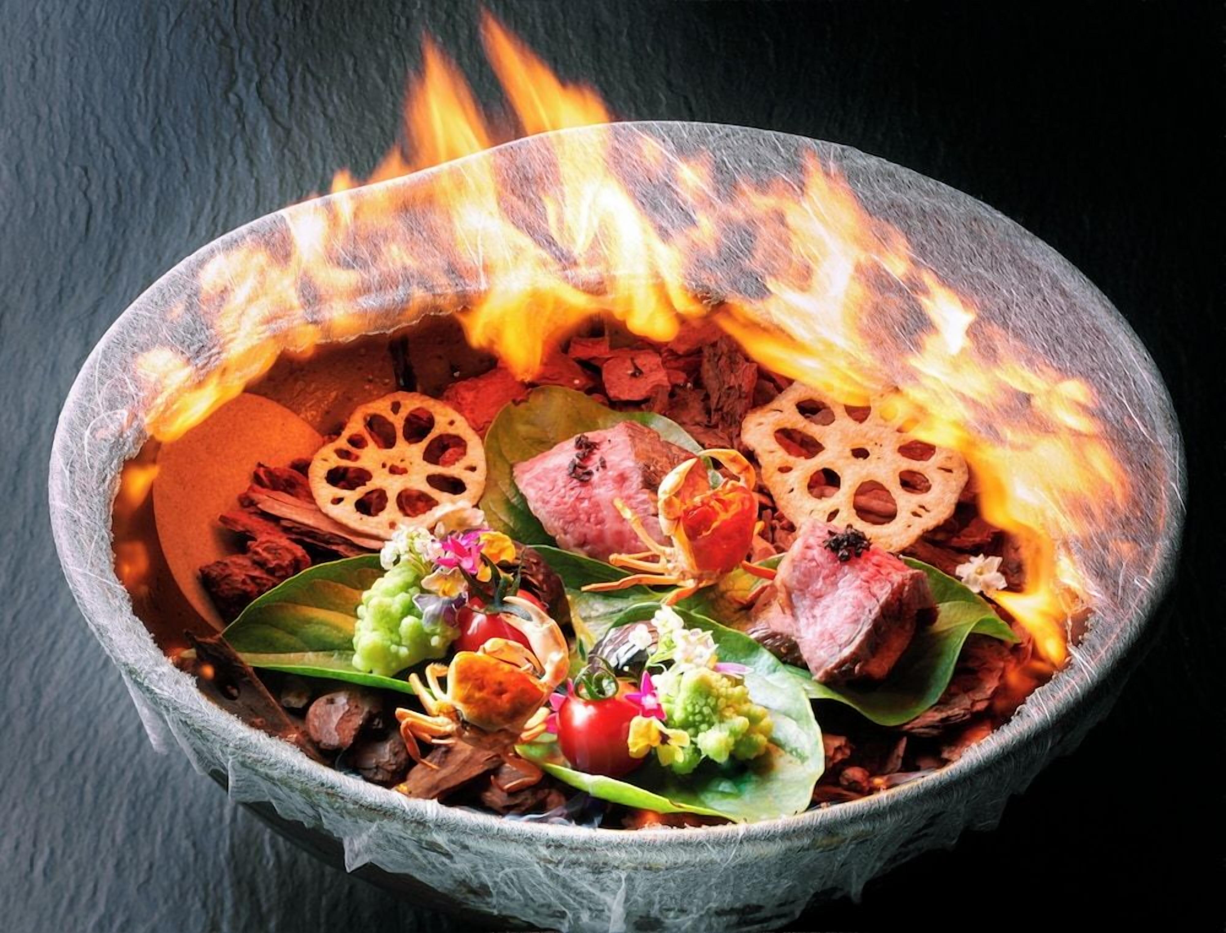 A bowl with food items and a fire burning above it.