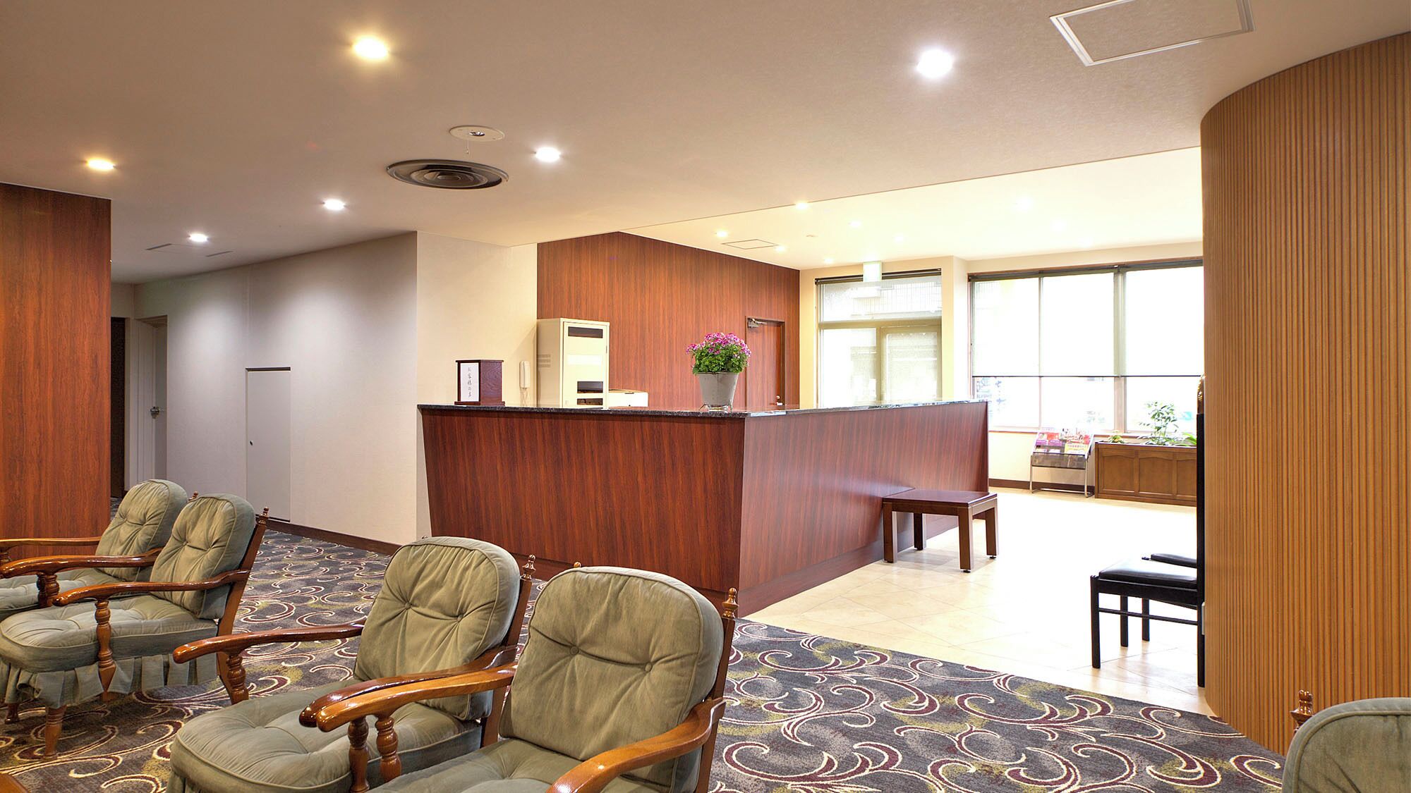 A hotel lobby with a reception desk, seating area, and large windows.