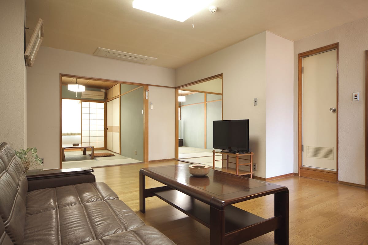 A living room with a sofa, a coffee table, a television, and a traditional Japanese sliding door.