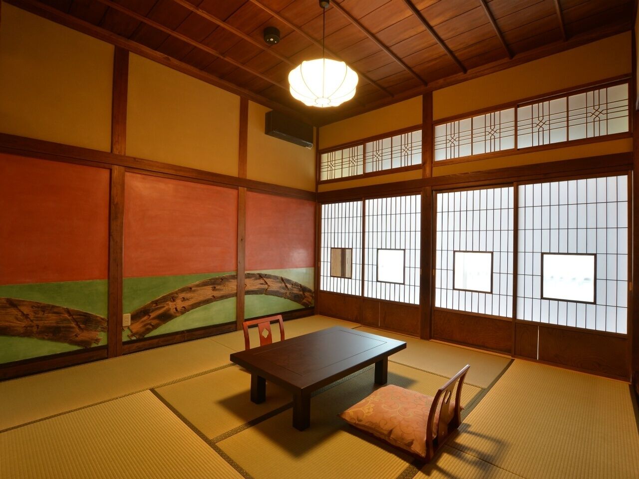 A traditional Japanese room with tatami flooring, a low table, and sliding doors with decorative patterns.