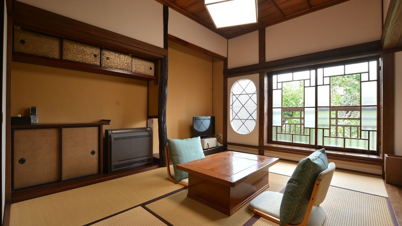 Une pièce de style japonais traditionnel, avec un sol recouvert de tatamis, une table basse et un téléviseur.