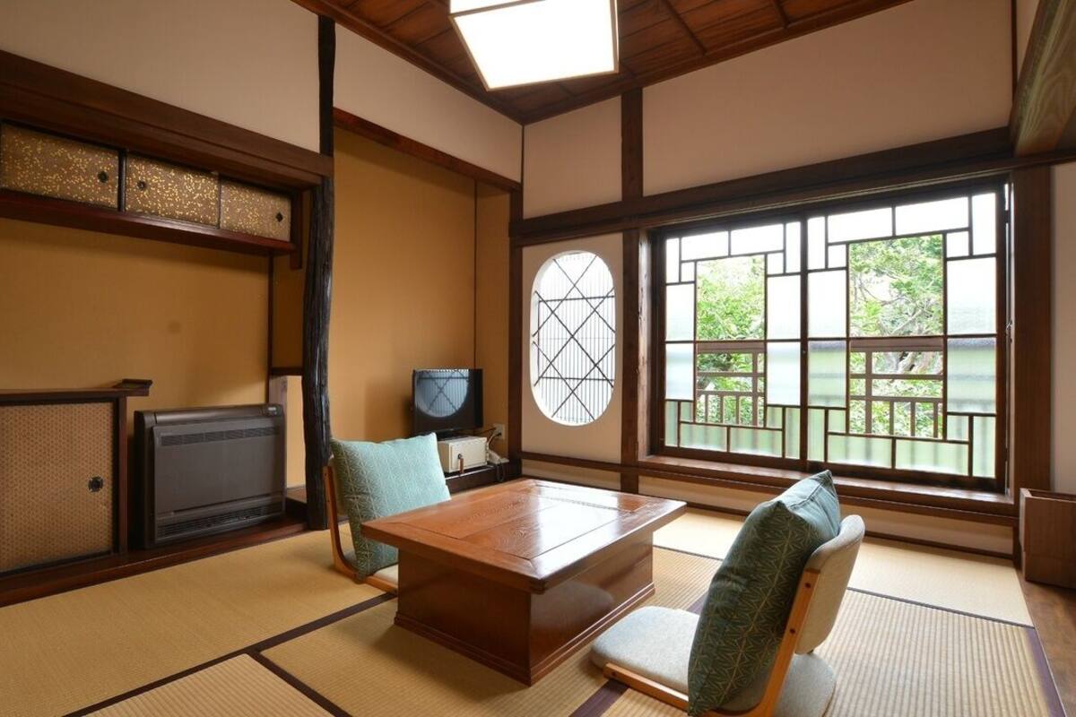 Ein traditioneller japanischer Raum mit Tatami-Böden, einem niedrigen Tisch und einem Fernseher.