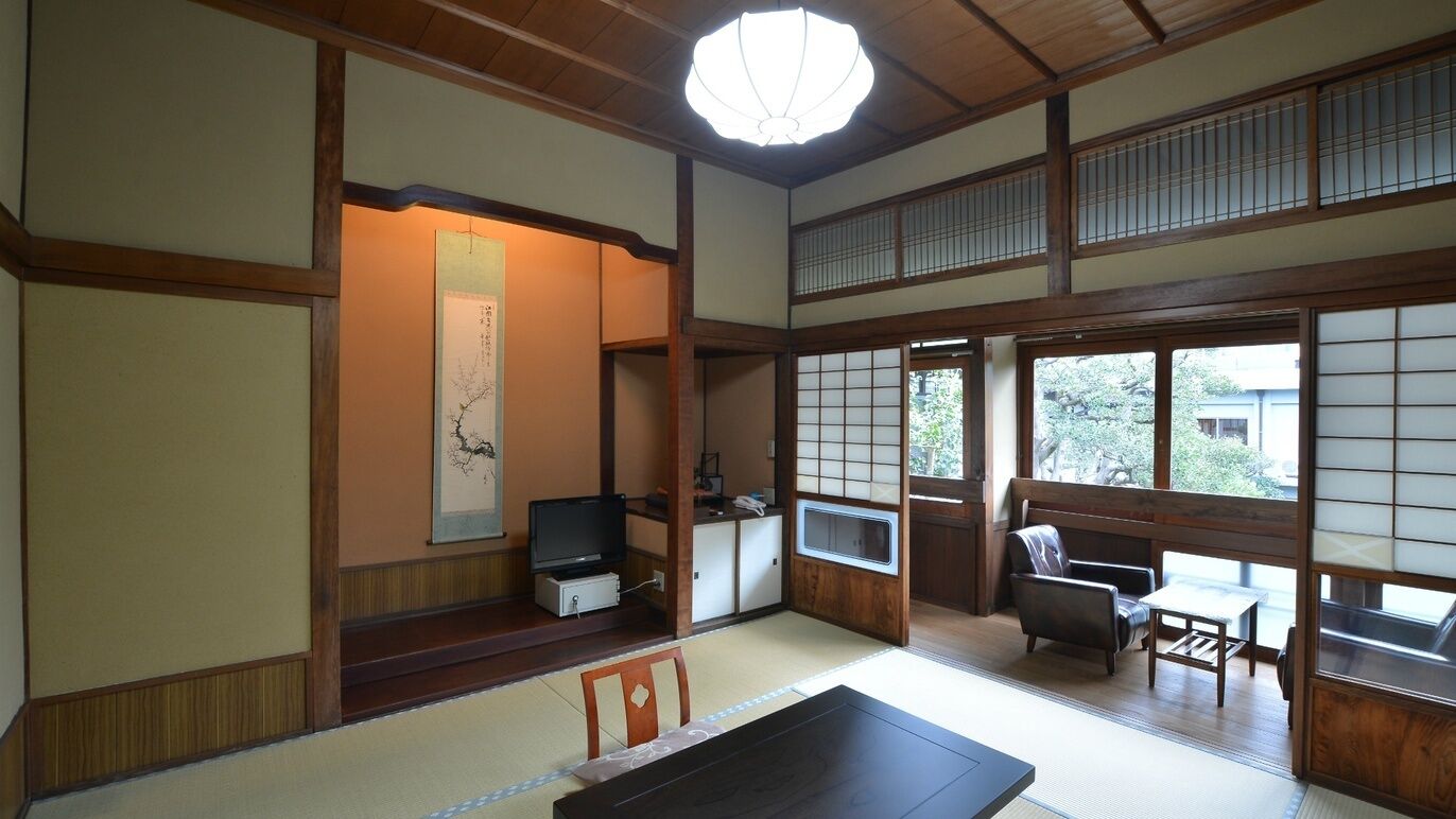 A traditional Japanese room with tatami flooring, a low table, and a television.