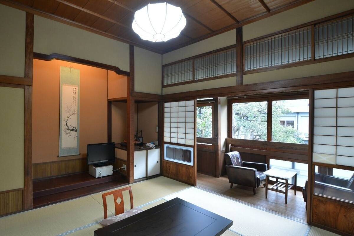 Ein traditioneller japanischer Raum mit Tatami-Böden, einem niedrigen Tisch und einem Fernseher.