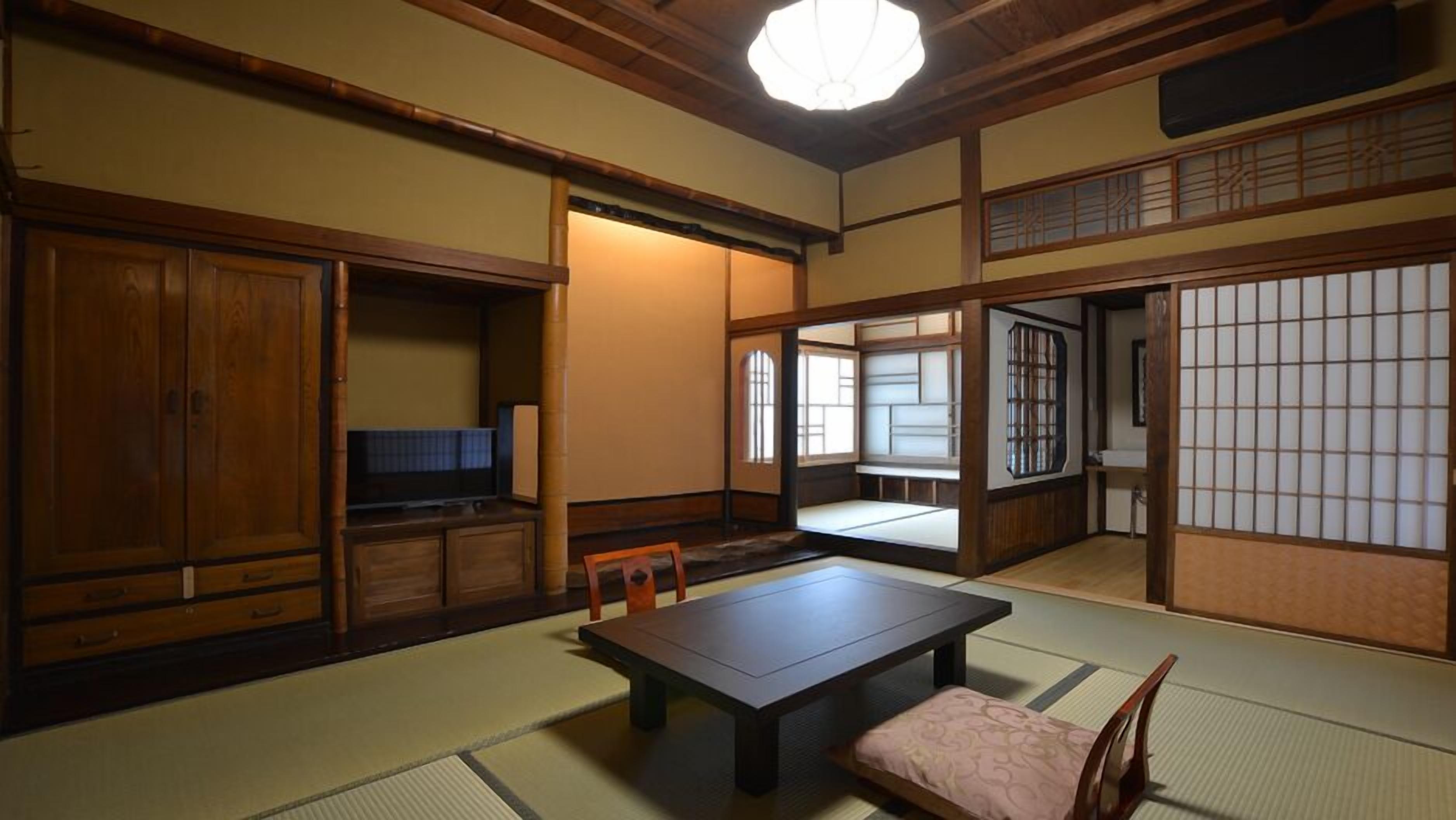 A traditional Japanese room with tatami flooring, a low table, a television, and sliding doors.