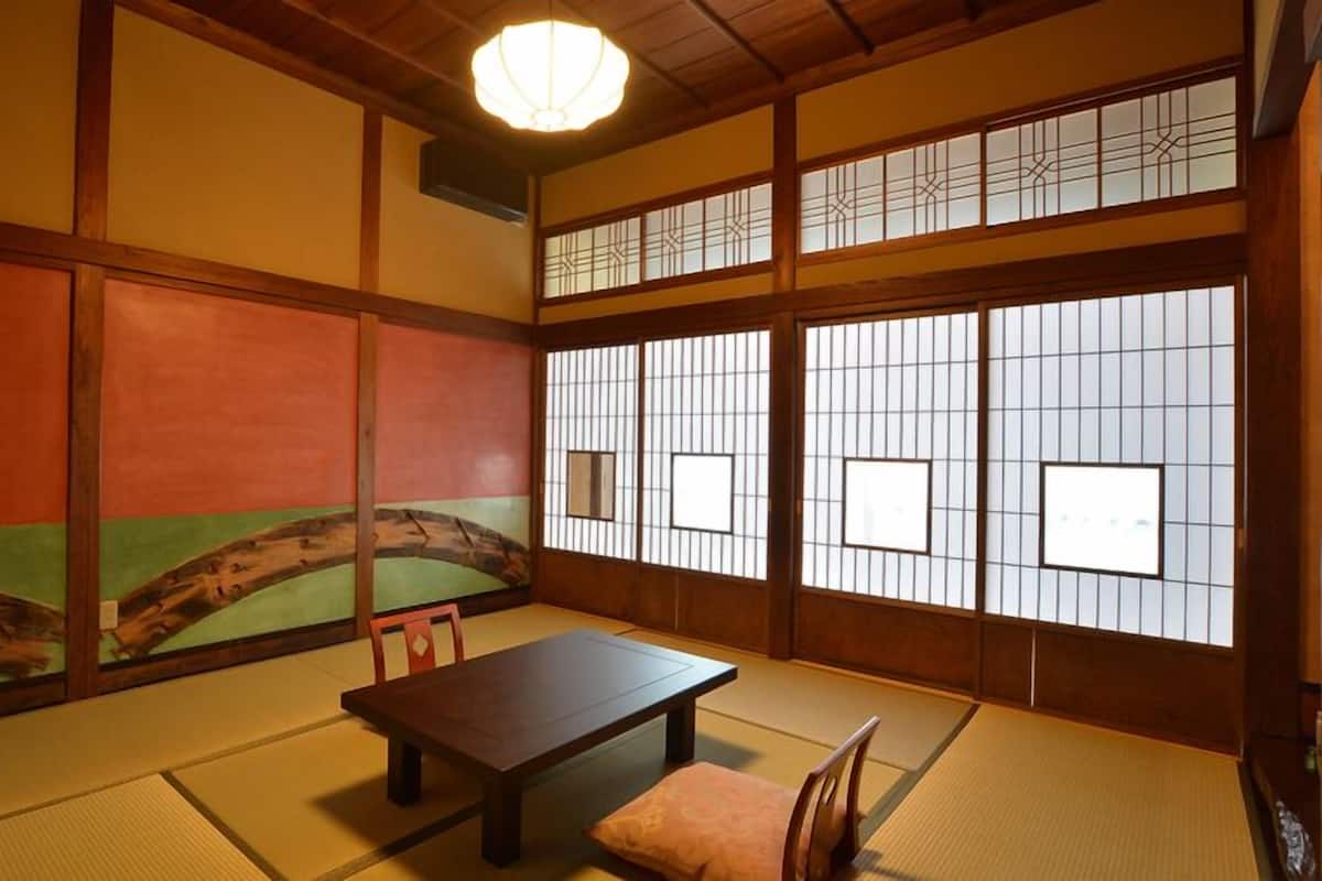 Ein traditioneller japanischer Raum mit Tatami-Böden, einem niedrigen Tisch und Shoji-Schirmwänden.