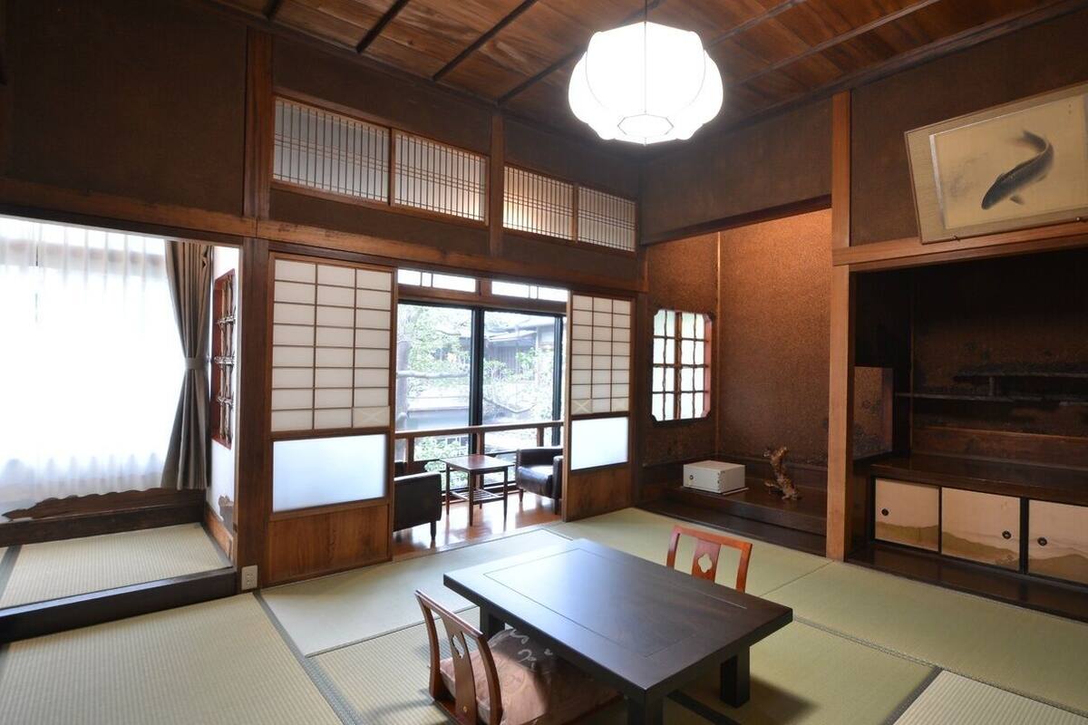 Ein traditioneller japanischer Raum mit Tatami-B öden, einem niedrigen Tisch und verschiebbaren Türen.