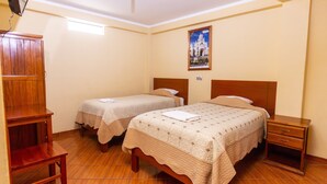 A hotel room with two single beds, a wooden nightstand, a wooden wardrobe, and a wall-mounted picture. - Hotel Tamia (Huaraz)