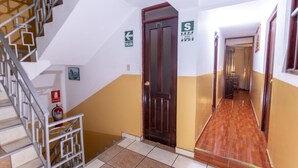 A hallway with a wooden door, a fire extinguisher, and a staircase. - Hotel Tamia (Huaraz)