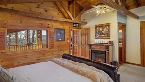 Een gezellig loghut slaapkamer met een groot bed, houten wanden, een open haard en een prachtig uitzicht door het raam.