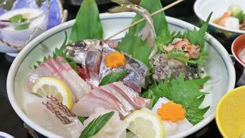 A bowl of assorted raw fish and vegetables on a table.