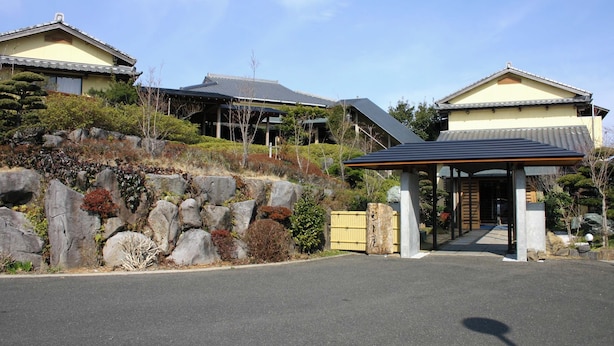 A traditional Japanese building with a covered entrance, stone pathway, and surrounding vegetation. - Ryotei Saigetsuan (Hirado)
