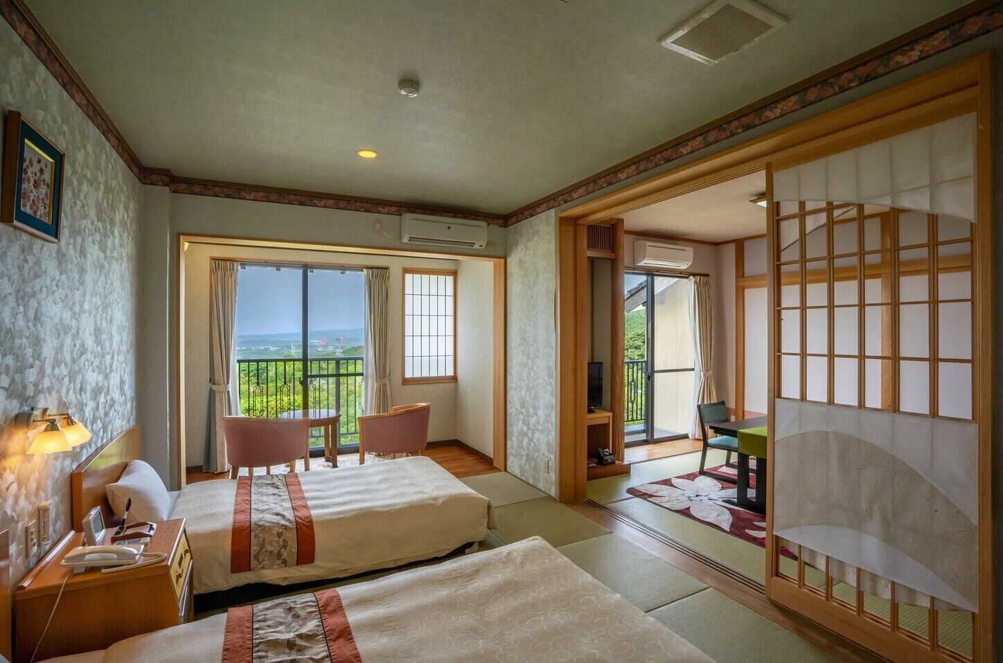 Une chambre d’hôtel avec deux lits, un balcon offrant une vue agréable et des portes coulissantes de style japonais traditionnel.