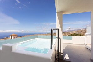 A rooftop infinity pool with a clear view of the ocean and distant hills.