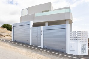 A modern building with two large garage doors, a white exterior, and a small utility box on the right side.