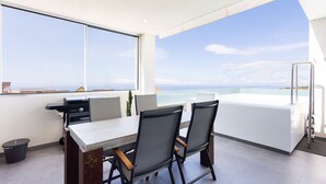 A modern outdoor dining area with a view of the ocean, a grill, and a white table with chairs. - 🌴☀️ Dream Vacation at Tulio Home Private Pool (Adeje)