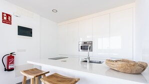 A modern kitchen with white cabinets, a stainless steel oven, and a wooden stool. - 🌴☀️ Dream Vacation at Tulio Home Private Pool (Adeje)