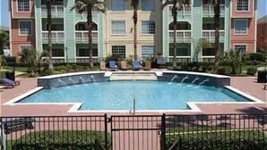 Un hôtel doté d’une piscine entourée de palmiers et d’un espace clos.