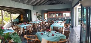 A restaurant with multiple tables, wicker chairs, and a stone wall backdrop. - ★★★★★Spectacular Water View-Private Wrap-Around Balcony-3 Pools-2 Restaurants ☼☼ (St. Thomas)