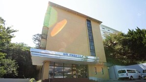 A building with a large glass facade, a sign with Japanese characters, and a white van parked outside. - Itoen Hotel Inatori (Higashiizu)
