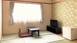 A room with tatami flooring, a low table, a sofa, a TV, and a small cabinet. - Itoen Hotel Inatori (Higashiizu)