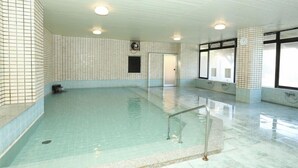 A large indoor swimming pool with tiled walls, a glass barrier, and a ceiling fan. - Itoen Hotel Inatori (Higashiizu)